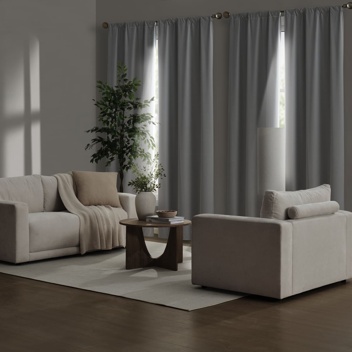 White Contractor Set panels drawn across two windows in a dim living room with a sofa, an armchair and a round wooden table