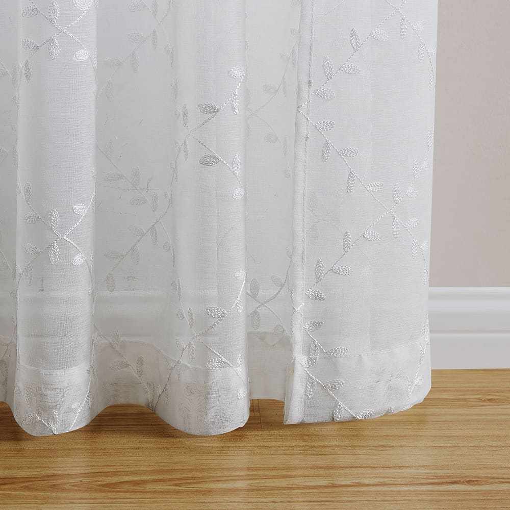 The bottom of a Leaf Embroidery white panel where it meets the floor