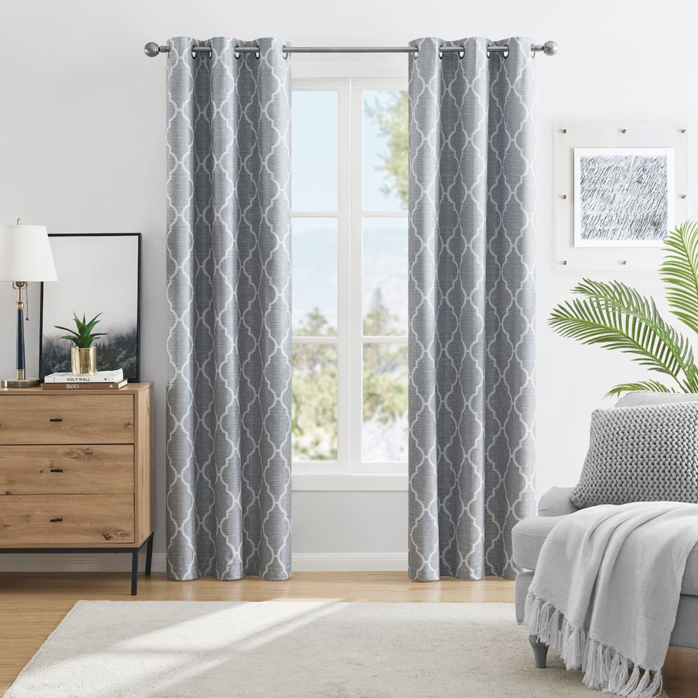 Trellis 100% blackout curtains in grey at a window in a furnished room